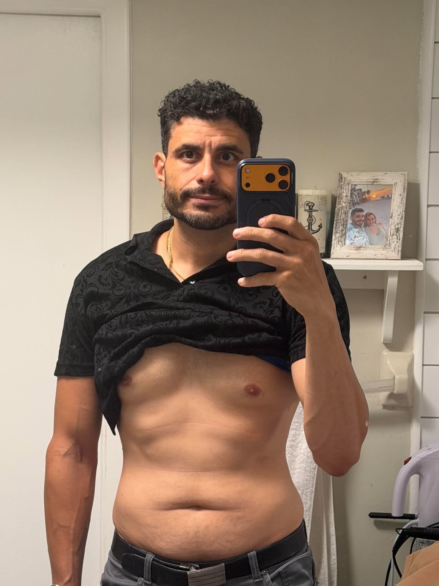Hector taking a progress photo in a black shirt