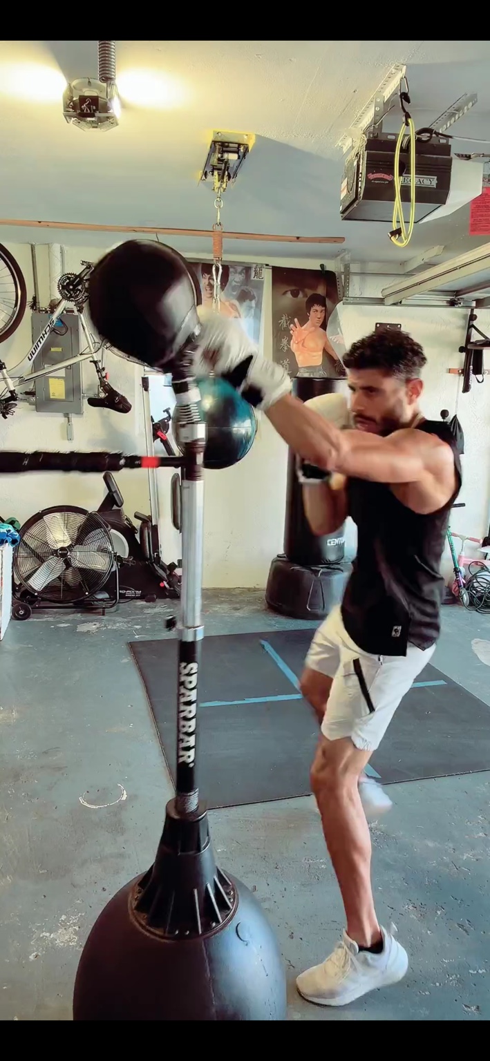 Hector striking a reflex boxing bag in his garage gym